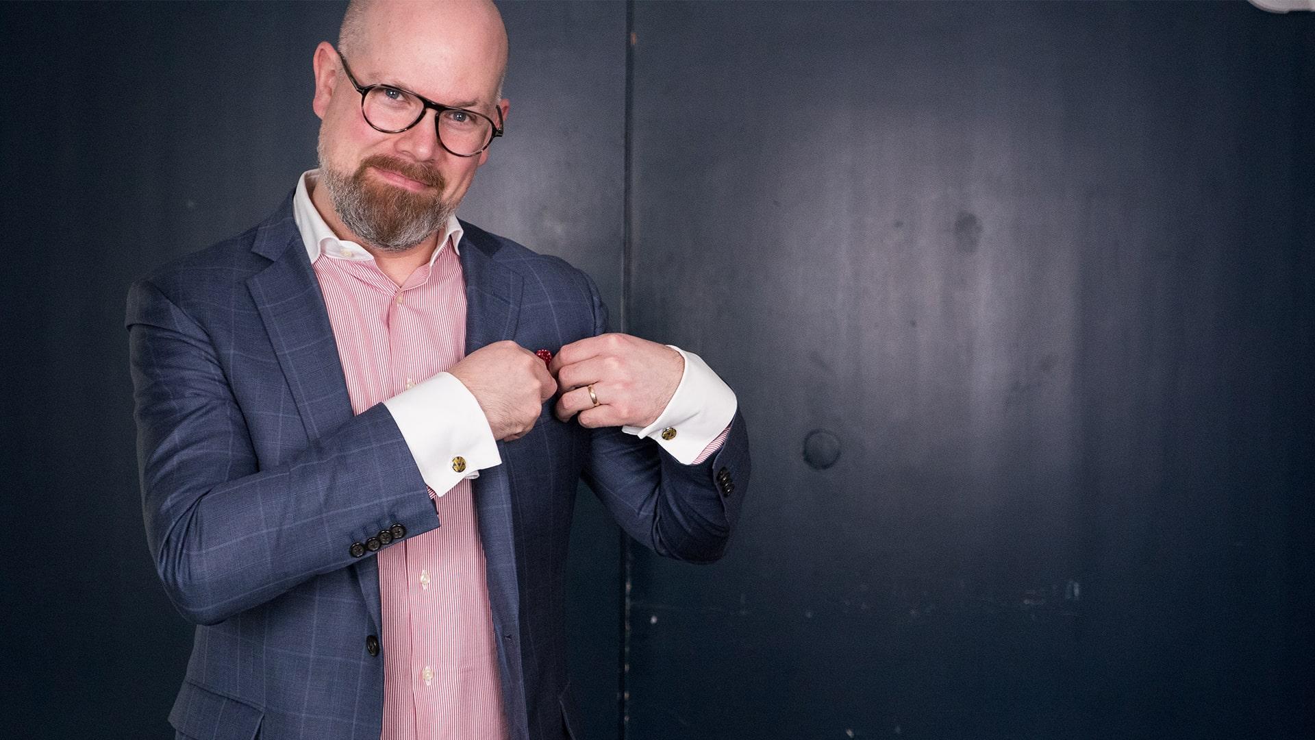 Philip Sherman, Radiokören. Man i glasögon ler och tittar in i kameran samtidigt som han rättar till en röd scarf som han har i bröstfickan på sin blårutiga kavaj. Han har en rödrandig skjorta med guldfärgade manschettknappar.