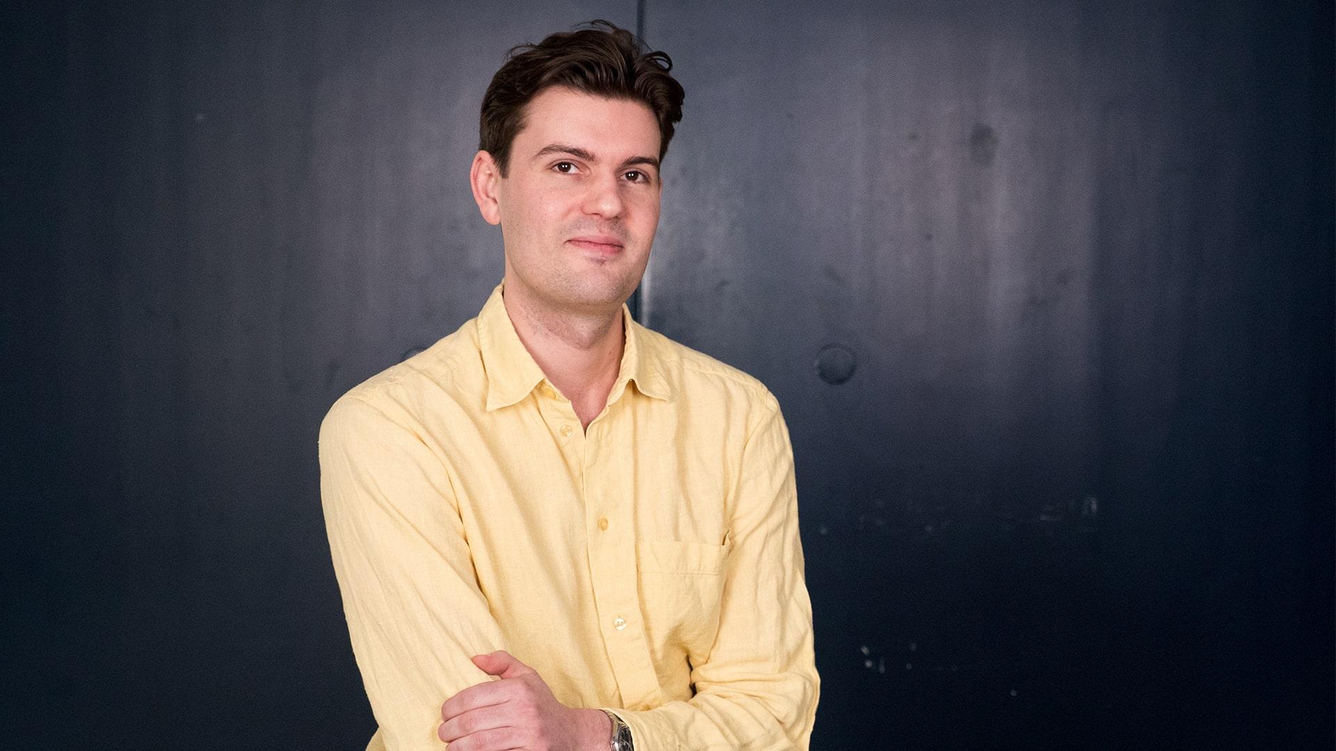 Karl Söderström, Radiokören. Bild på leende man som tittar in i kameran. Han har brunt kortklippt hår och är klädd i en gul skjorta.