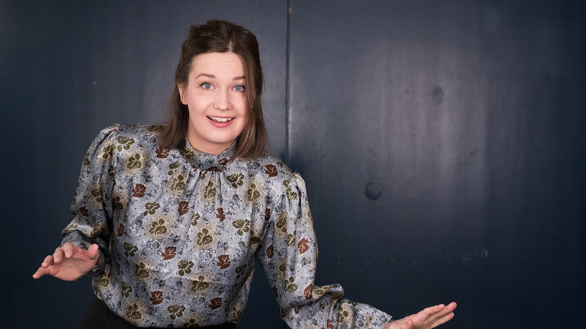 Kathrine Lorenzen, Radiokören. Bild på leende kvinna i brun pagefrisyr som gestikulerar med händerna. Hon har en bladmönstrad blus i grått, brunt och grönt.