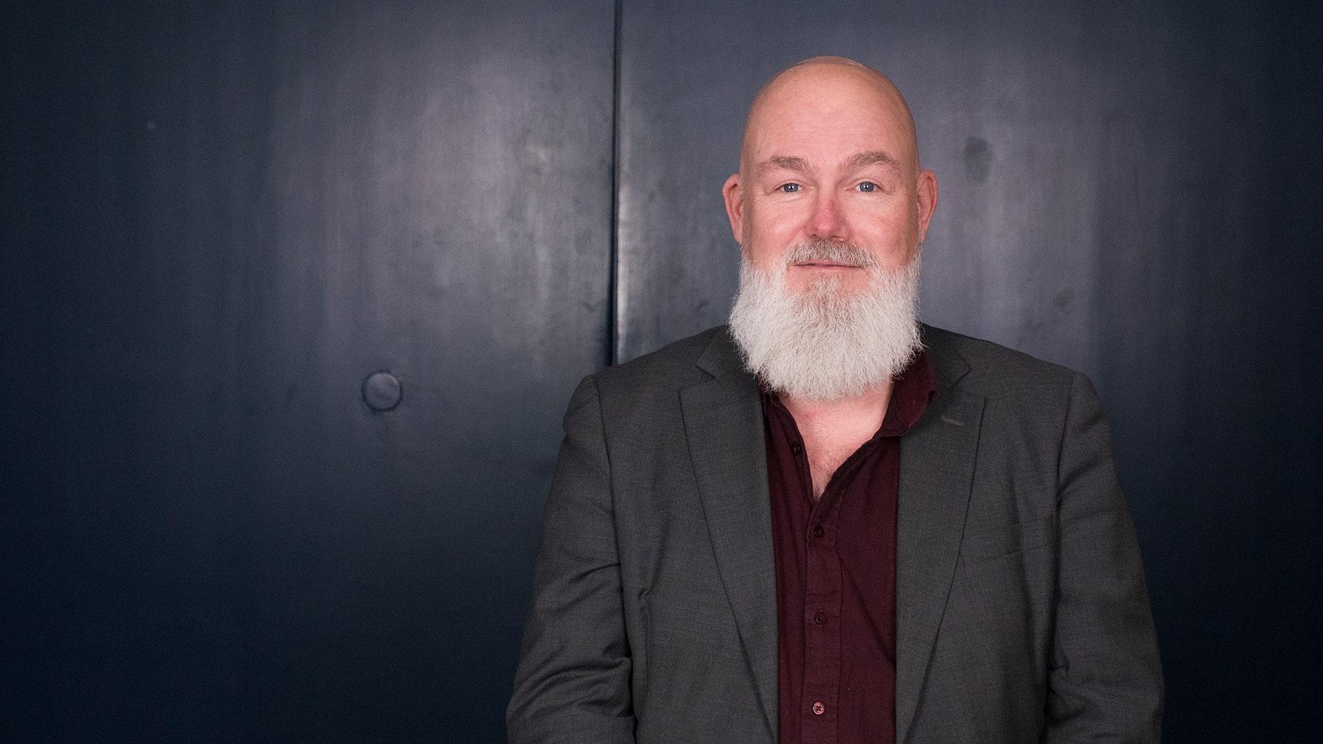 Mathias Brorson, Radiokören. Bild på man i vitt långt skägg, klädd i vinröd skjorta och grå kavaj.