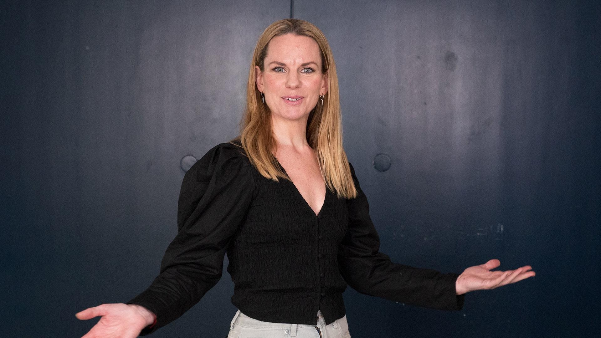 Elin Skorup, Radiokören. Leende kvinna med långt ljust hår tittar rakt mot kameran och slår ut med händerna i en välkomnande gest.