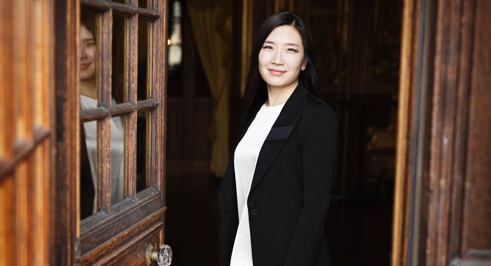 Dirigenten Eun Sun Kim står i en dörröppning och ler.